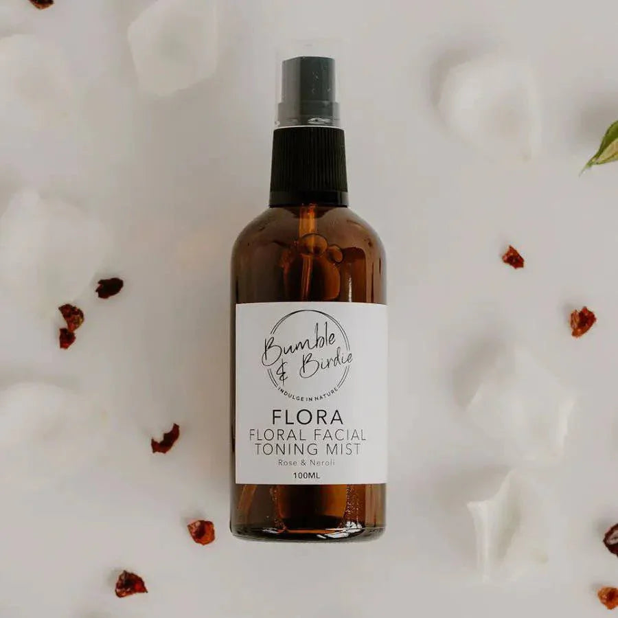 Flora facial toning mist in an amber spray bottle by Bumble & Birdie, with petals