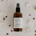 Flora facial toning mist in an amber spray bottle by Bumble & Birdie, with petals