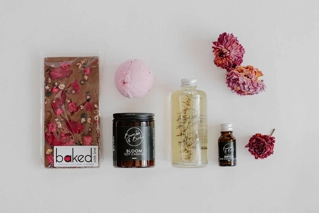 Lovers Lane set laid out: berry chocolate block, bath bomb, Bloom jar candle, body oil and essential oil