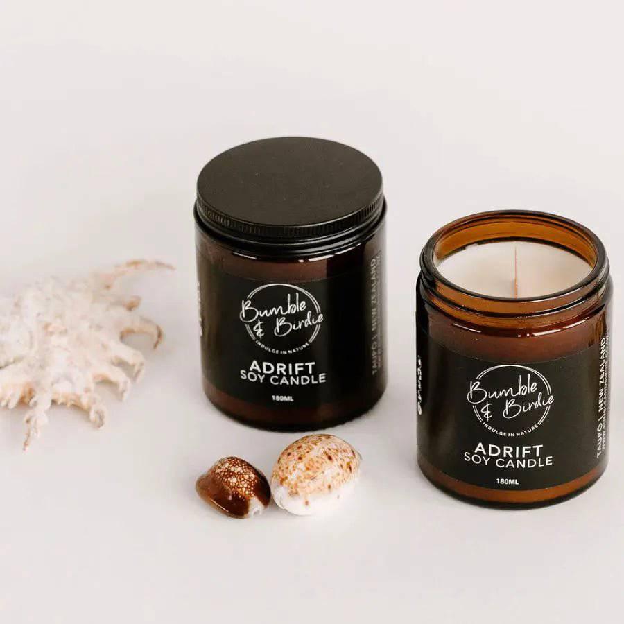 Two Adrift soy jar candles, one lidded and one open, with shells