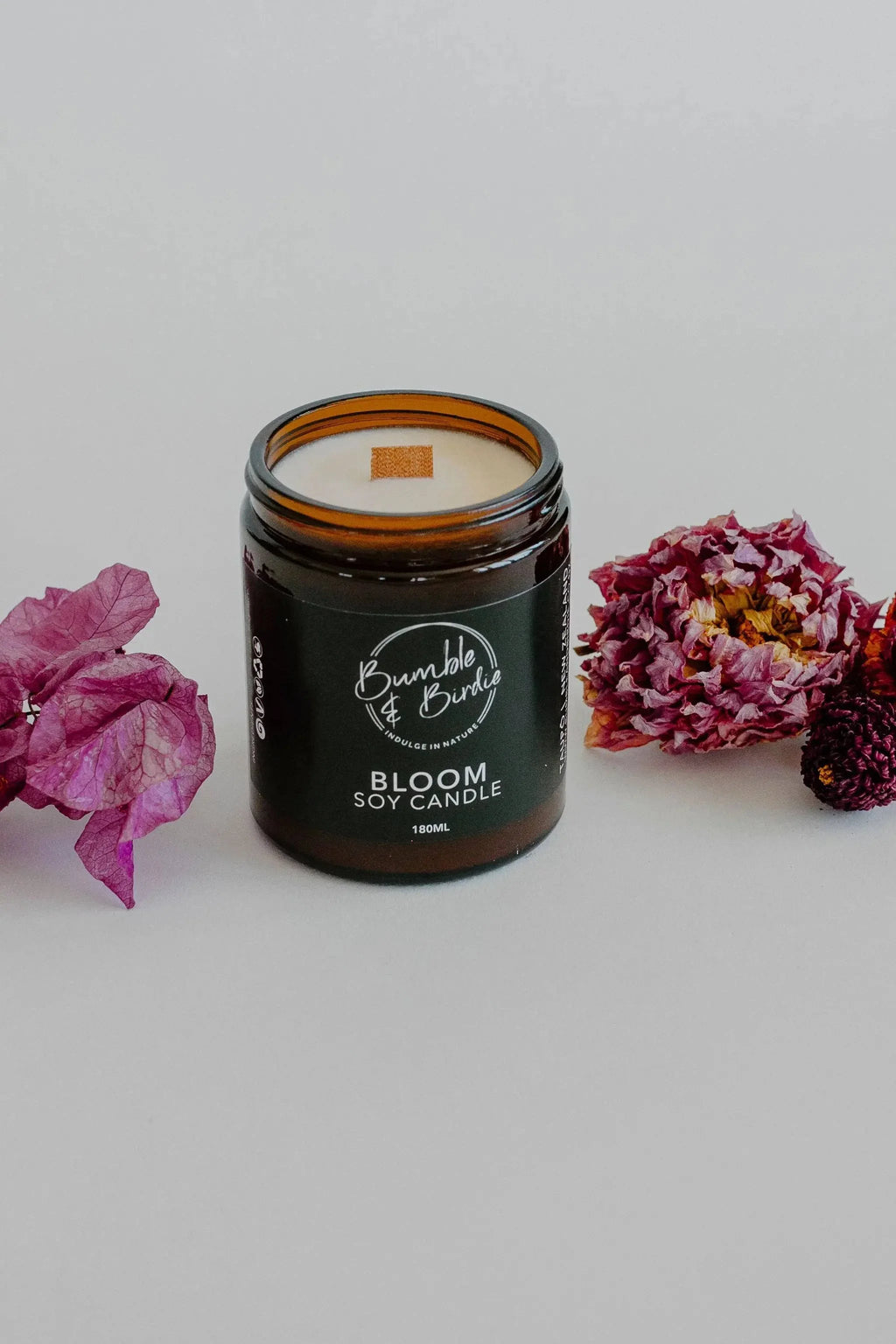 Bloom soy candle in an amber glass jar by Bumble & Birdie, with pink flowers
