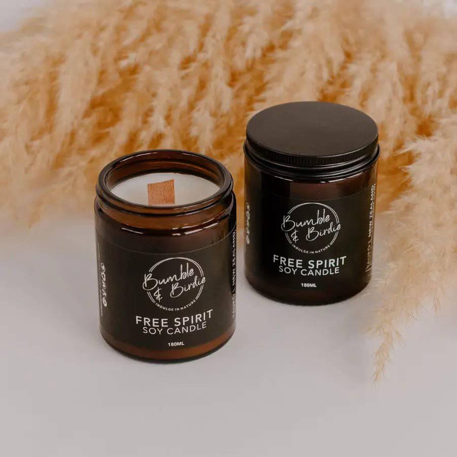 Two Free Spirit soy jar candles by Bumble & Birdie, one open with a wood wick, with pampas grass