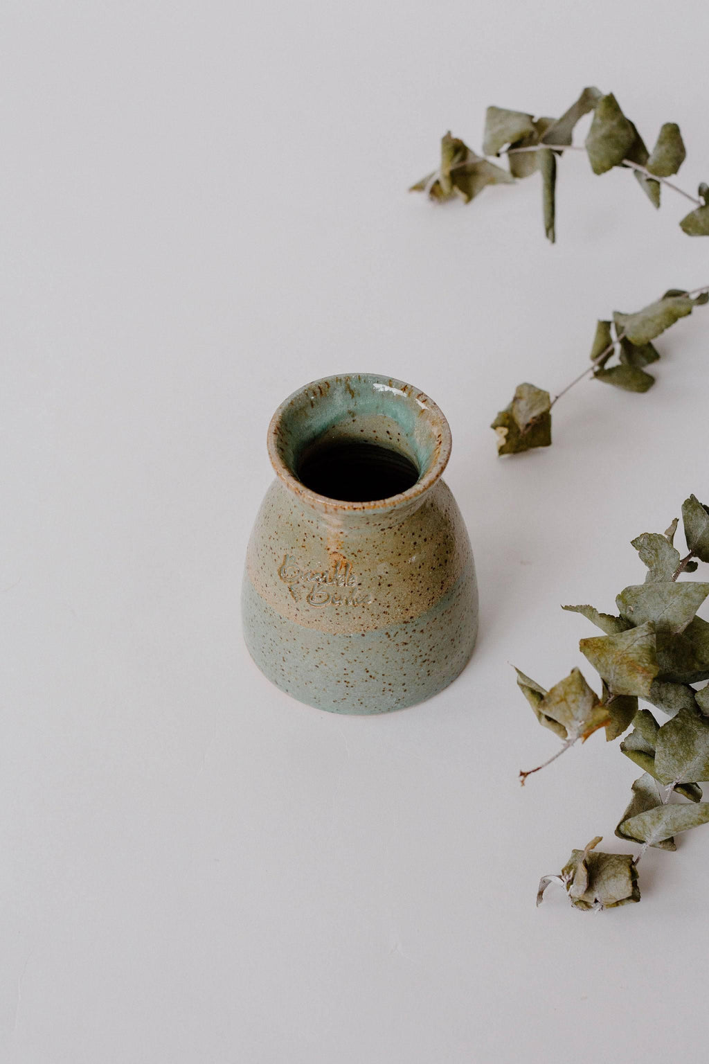 Earth Brush Haven green-glazed pottery vase beside eucalyptus sprigs