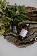 Homegrown Self-care Ritual Set: Into the Ngahere night serum and oil cleanser on driftwood with leaves