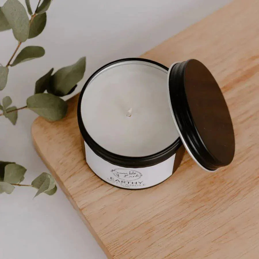 Earthy soy tin candle with the lid off, on a wooden board