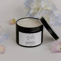 Harvest soy candle in an open black tin by Bumble & Birdie, with hydrangea petals