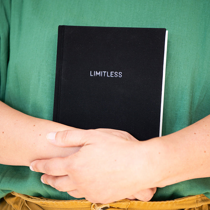 Person holding the black "Limitless" I Am... Mindset Journal