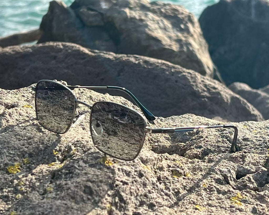 URBA VISTA Logan sunglasses resting on a rock by the sea