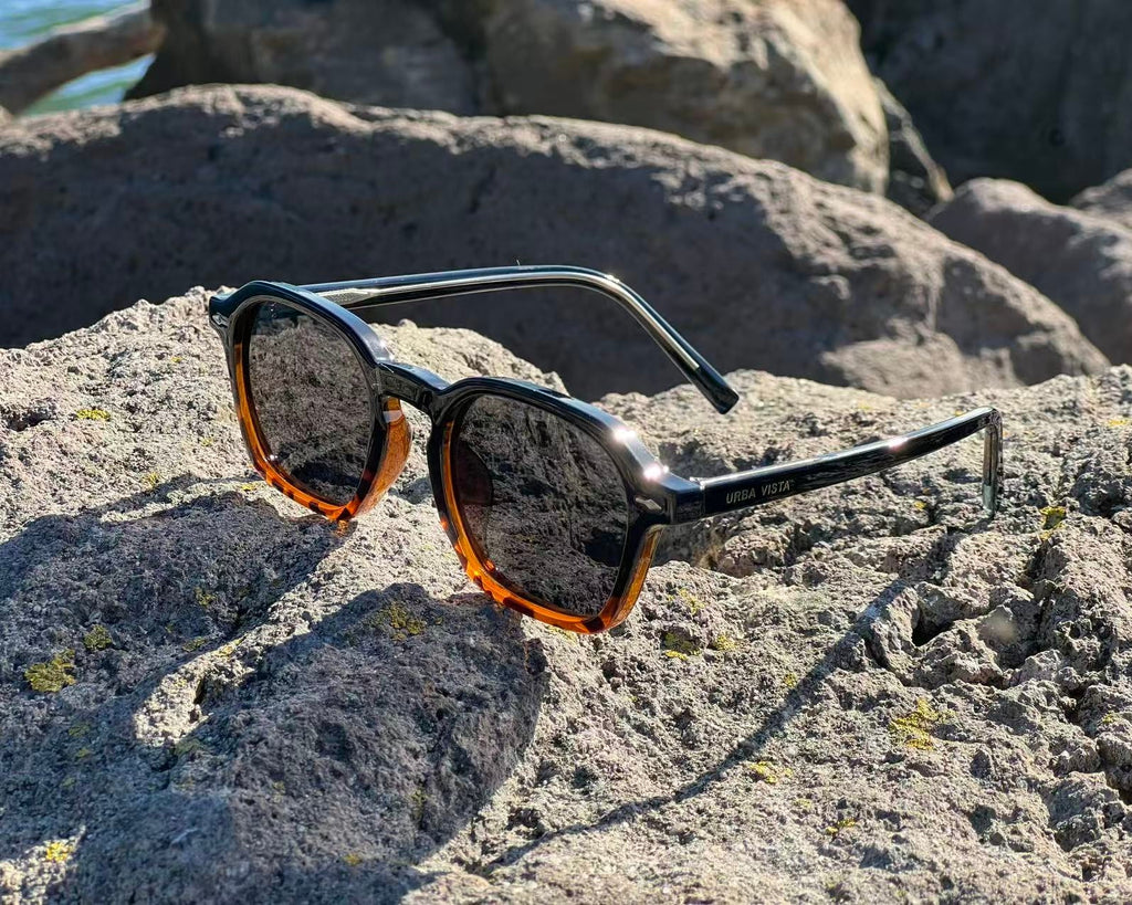 URBA VISTA Henry sunglasses resting on a rock by the sea